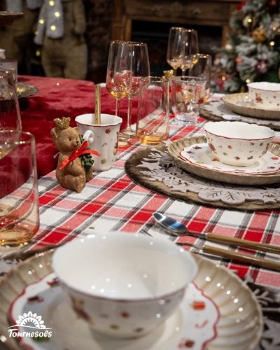 Table de Noël décorée avec vaisselle festive et décorations rustiques.